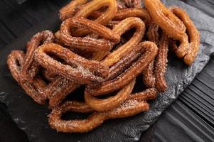 churros caseros sobre un fondo negro de madera. foto