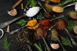 Colorful various herbs and spices for cooking on dark wooden rustic background photo