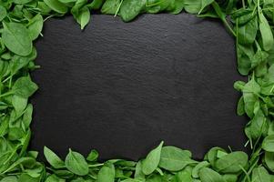 Kitchen table with stone cutting board, decorated with herbs. Presented on the black wooden background with center empty space. Table top view. photo