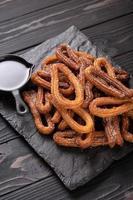 Homemade churros with chocolate on a dark wooden rustic background. photo