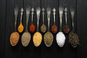 Colorful various herbs and spices for cooking on dark wooden rustic background photo