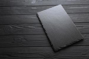 Black stone slate plate on a black stone background. Free copy space. photo