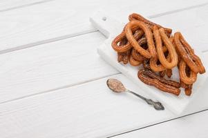 churros caseros sobre un fondo blanco de madera. foto