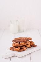 Homemade churros with milk and cream on a white wooden background. photo