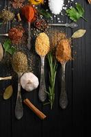 Colorful various herbs and spices for cooking on dark wooden rustic background photo