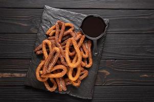 churros caseros con chocolate sobre un fondo rústico de madera oscura. foto