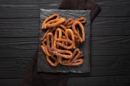 Homemade churros with chocolate on a dark wooden rustic background. photo