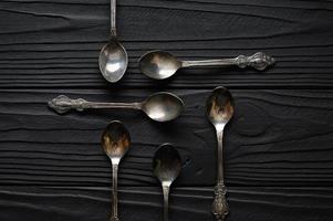 Directly above a shot of old spoons on a black table photo