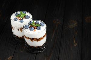 Homemade layered dessert with fresh blueberries, cream cheese or yogurt, granola on rustic background. photo