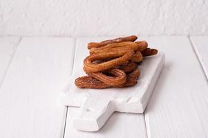 churros caseros sobre un fondo blanco de madera. foto