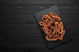 Homemade churros on a wooden black background. photo