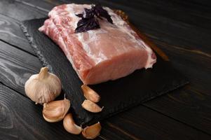 A large piece of pork loin with basil on a rustic dark background. photo