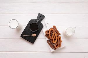 Homemade churros with chocolate on a white wooden background. photo