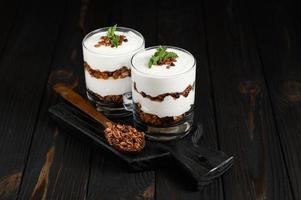 Layered dessert with granola on a wooden dark wooden background. photo