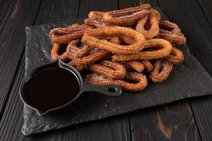 Homemade churros with chocolate on a dark wooden rustic background. photo