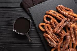 Homemade churros with chocolate on a dark wooden rustic background. photo