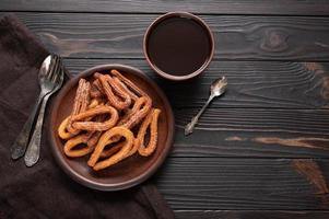 churros caseros con chocolate sobre un fondo rústico de madera oscura. foto