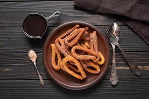 churros caseros con chocolate sobre un fondo rústico de madera oscura. foto