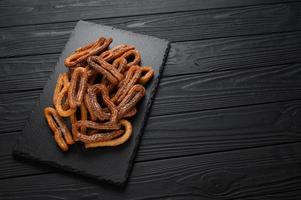 Homemade churros on a wooden black background. photo