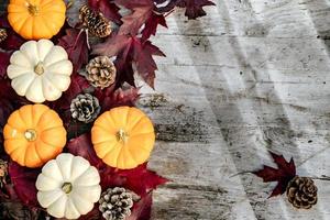 calabazas, hojas secas y pino con composición otoñal sobre fondo de madera. otoño, otoño, concepto de halloween. endecha plana, vista superior, espacio de copia foto