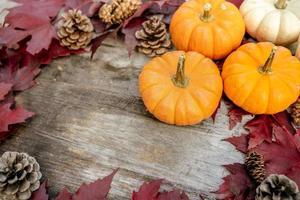 calabazas, hojas secas y pino con composición otoñal sobre fondo de madera. otoño, otoño, concepto de halloween. endecha plana, vista superior, espacio de copia foto