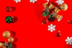 concepto de fondo de navidad. vista superior de campanas doradas navideñas con decoración de bolas, ramas de abeto, estrellas y copos de nieve sobre fondo rojo. foto