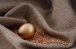 Golden egg on gold sand in waves of cloth. photo