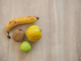 Healthy and ripe fruits on a wooden table. Banana, apples and kiwi fruit. photo