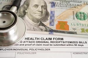 formulario de reclamación de salud con estetoscopio y billetes en dólares estadounidenses, concepto médico de accidente de seguro. foto