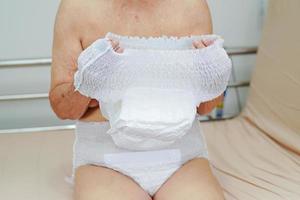 Asian elder senior woman patient wearing adult incontinence diaper pad in hospital. photo