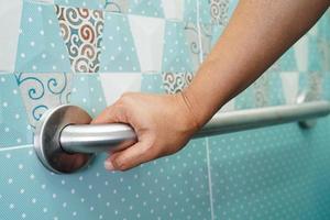 Asian woman patient use toilet support rail in bathroom, handrail safety grab bar, security in nursing hospital. photo