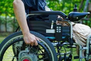 Asian elderly woman disability patient sitting on electric wheelchair in park, medical concept. photo