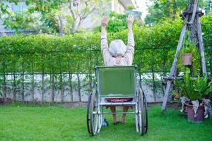Asian elderly woman disability patient sitting on electric wheelchair in park, medical concept. photo