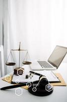 Justice and law concept.Male judge in a courtroom with the gavel, working with, computer and docking keyboard, eyeglasses, on table in morning light photo