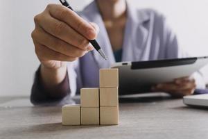 businessman hand stack woods block step on table. business development concept.arranging wood block with icon business strategy and Action plan. photo