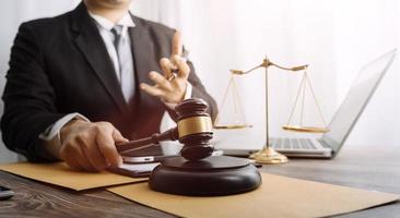 Justice and law concept.Male judge in a courtroom with the gavel, working with, computer and docking keyboard, eyeglasses, on table in morning light photo