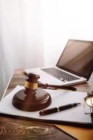 Justice and law concept.Male judge in a courtroom with the gavel, working with, computer and docking keyboard, eyeglasses, on table in morning light photo