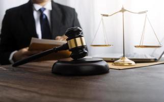 Justice and law concept.Male judge in a courtroom with the gavel, working with, computer and docking keyboard, eyeglasses, on table in morning light photo