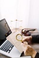 Justice and law concept.Male judge in a courtroom with the gavel, working with, computer and docking keyboard, eyeglasses, on table in morning light photo