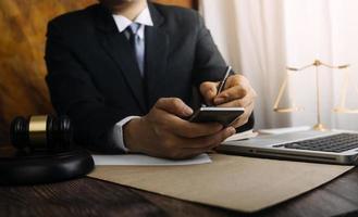 Justice and law concept.Male judge in a courtroom with the gavel, working with, computer and docking keyboard, eyeglasses, on table in morning light photo