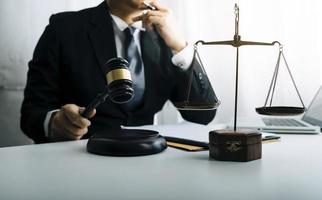 Justice and law concept.Male judge in a courtroom with the gavel, working with, computer and docking keyboard, eyeglasses, on table in morning light photo