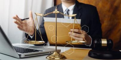 Justice and law concept.Male judge in a courtroom with the gavel, working with, computer and docking keyboard, eyeglasses, on table in morning light photo