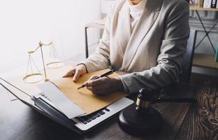 Justice and law concept.Male judge in a courtroom with the gavel, working with, computer and docking keyboard, eyeglasses, on table in morning light photo