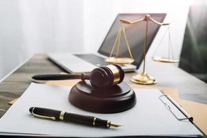 Justice and law concept.Male judge in a courtroom with the gavel, working with, computer and docking keyboard, eyeglasses, on table in morning light photo