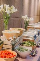arreglo floral para la boda de verano, hecho de rosas y ramas verdes en una mesa en el restaurante. , vidrio y platos en el restaurante al aire libre en un día ventoso con efecto de grano de película foto