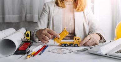 Two colleagues discussing data working and tablet, laptop with on on architectural project at construction site at desk in office photo