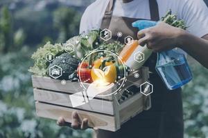 un hombre de negocios futurista cultiva verduras y cultivos usando tecnología moderna de inteligencia artificial usando teléfonos móviles, sensores de temperatura y humedad, rastreo de agua, control climático, íconos de datos holográficos. foto