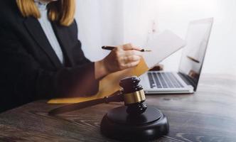 Justice and law concept.Male judge in a courtroom with the gavel, working with, computer and docking keyboard, eyeglasses, on table in morning light photo