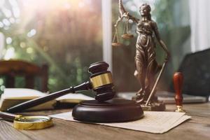 Justice and law concept.Male judge in a courtroom with the gavel, working with, computer and docking keyboard, eyeglasses, on table in morning light photo