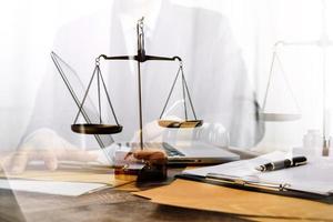 Justice and law concept.Male judge in a courtroom with the gavel, working with, computer and docking keyboard, eyeglasses, on table in morning light photo